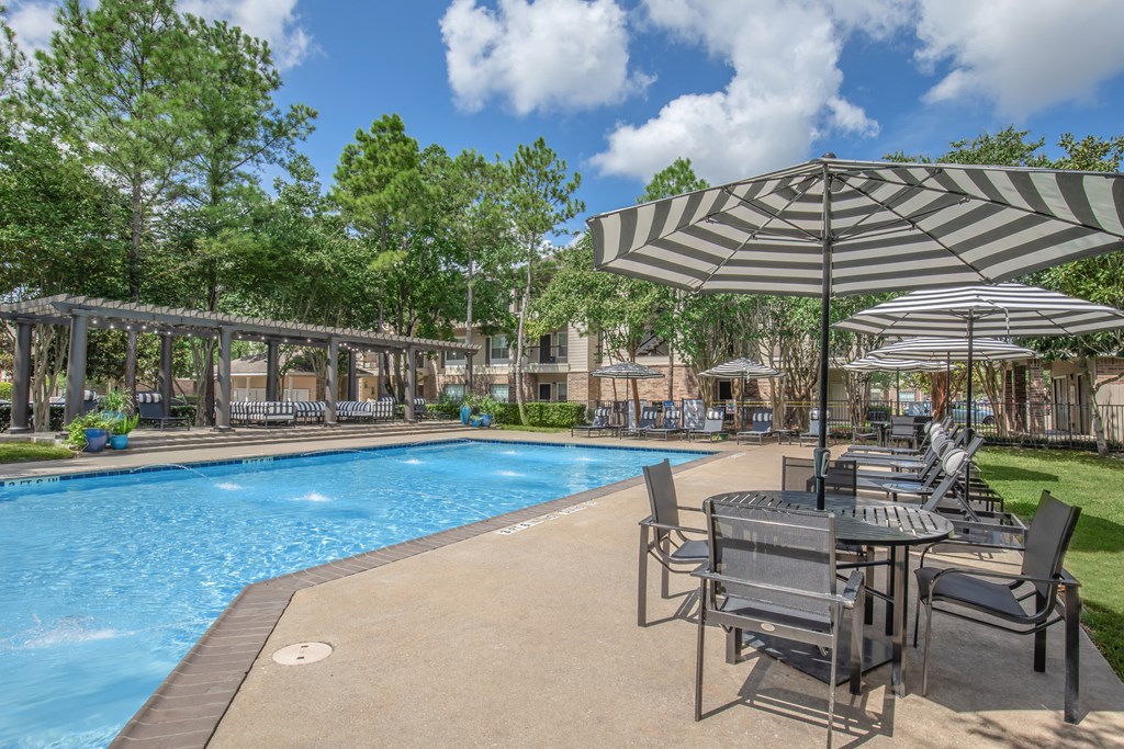 Apartments In Houston Texas for Rent – Westchase Forest - Photo of a swimming pool with tables and umbrellas next to it