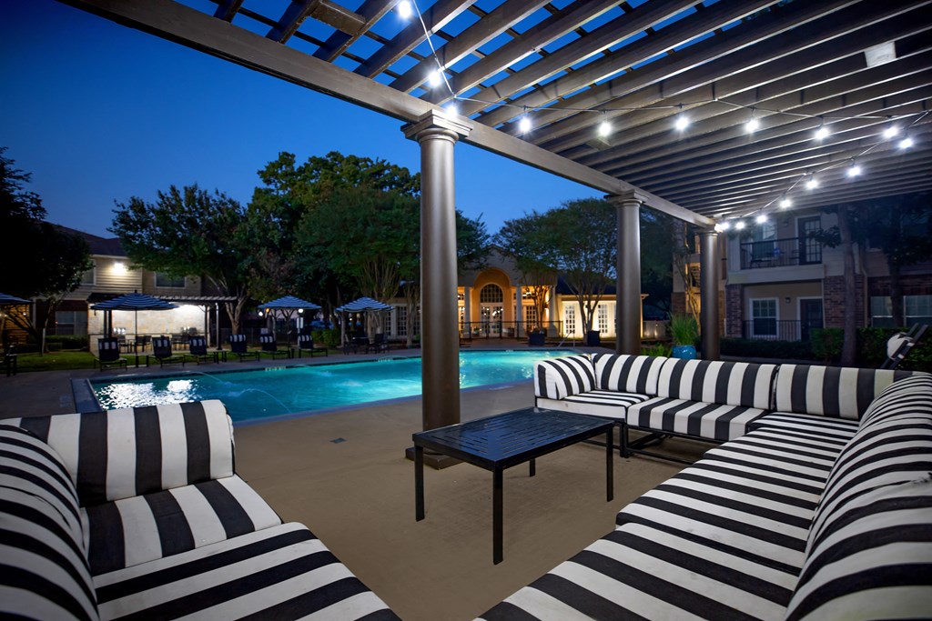 Affordable Houston Texas Apartments – Westchase Forest – Photo of a swimming pool with black and white striped lounge chairs under a patio