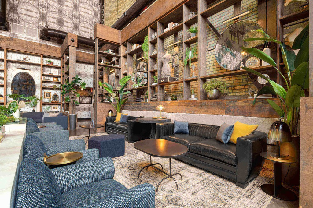 a lobby with couches and chairs and a wall filled with plants