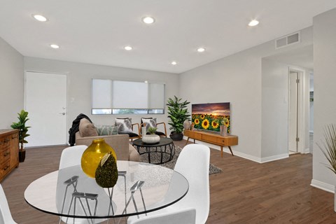 A modern dining room with a glass table and white chairs.