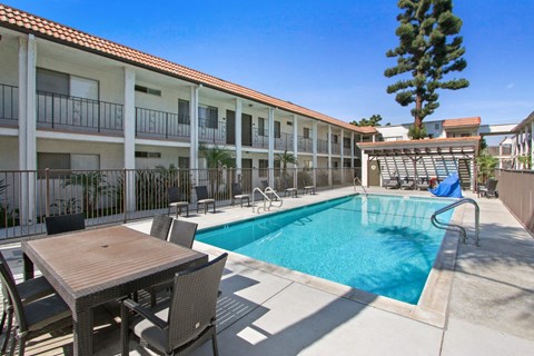 A pool with a table and chairs in front of a building.