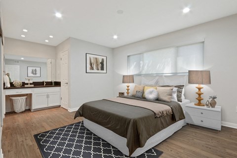 A bedroom with a large bed and a rug on the floor.