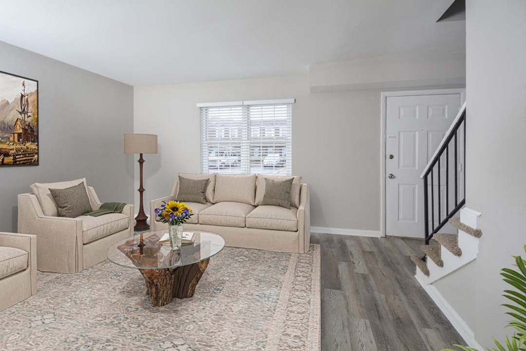 A living room with a glass coffee table and a couch.