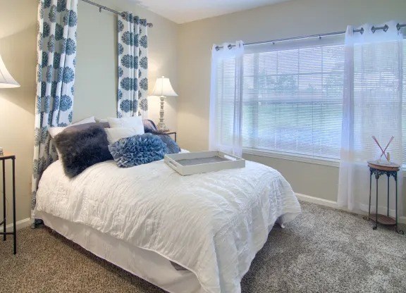 Comfortable bedroom with large window and plush carpeting at Enclave at Wolfchase Apartments in Cordova, TN.