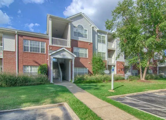 A multi-story apartment building with a green lawn in front.