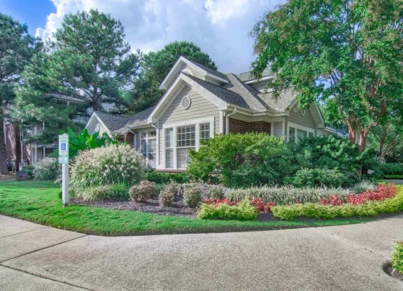 A house with a well-maintained lawn and a sign in front.