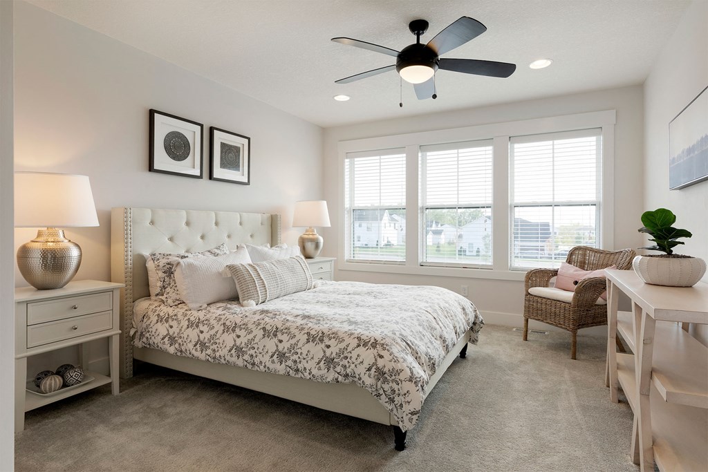 A bedroom with a large bed and a ceiling fan.