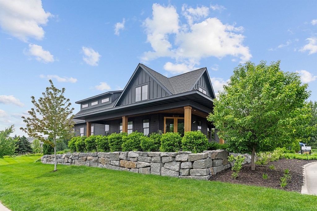 A modern house with a stone wall in front.