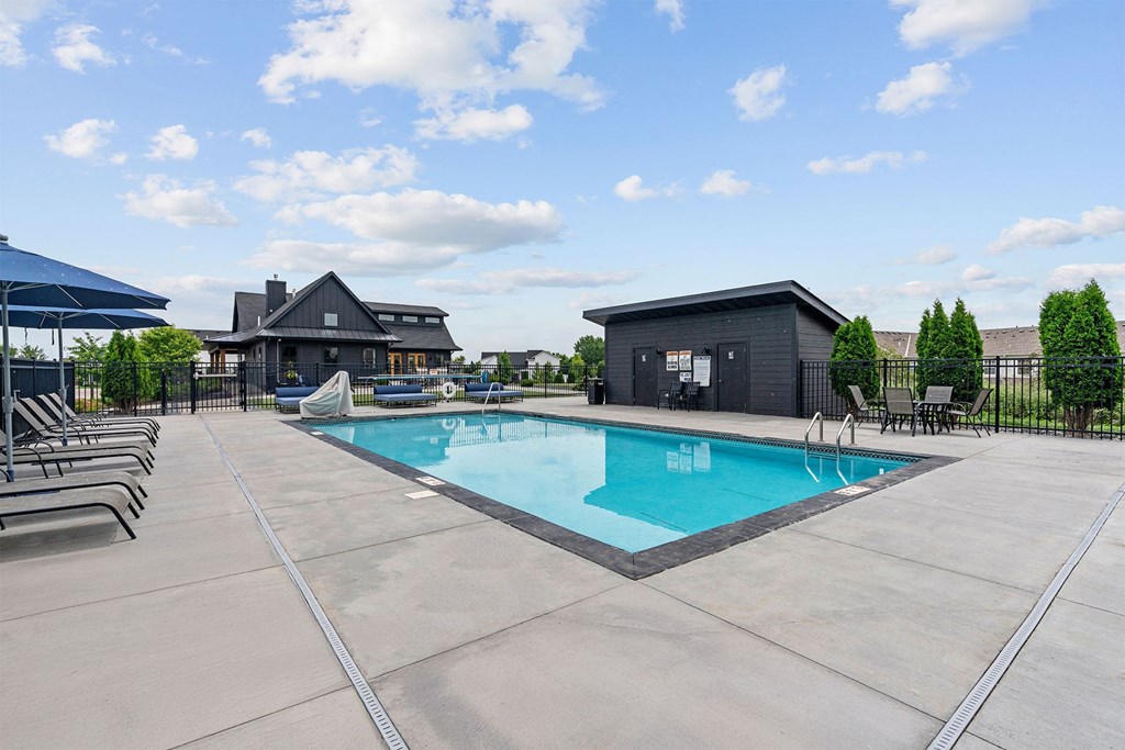 A large outdoor swimming pool with a blue sky and clouds in the background.