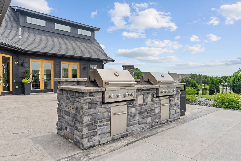 A stone outdoor kitchen with a grill and oven.