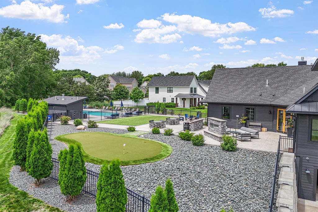 A backyard with a putting green and a pool.