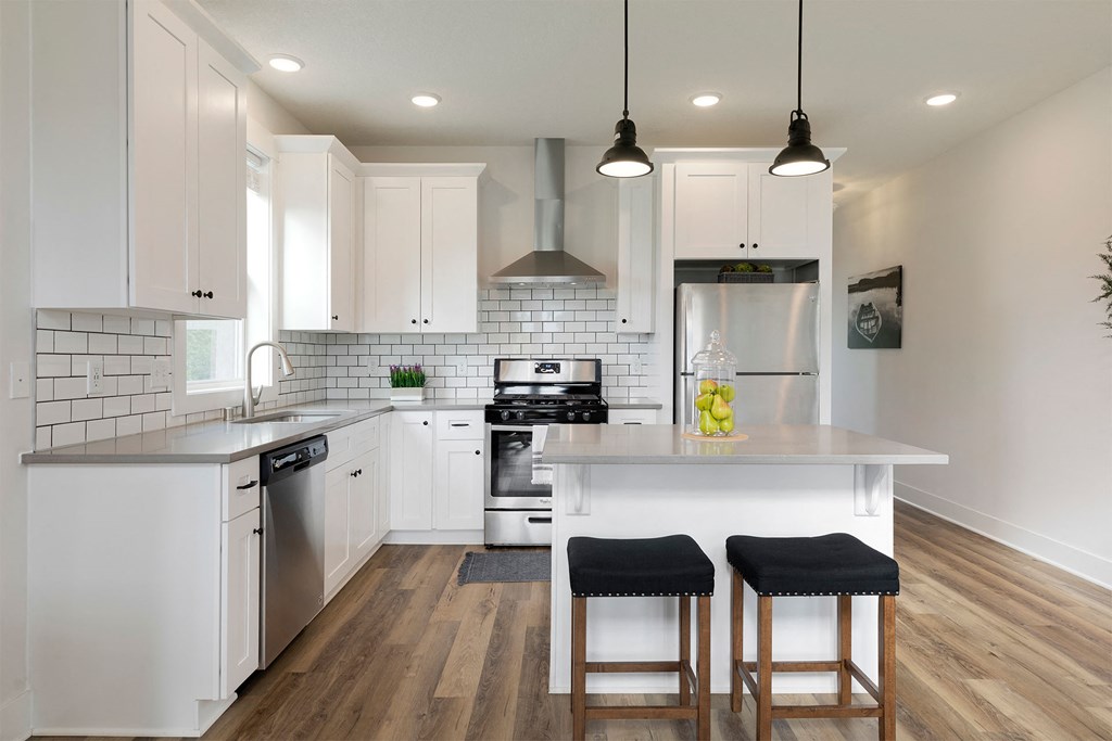 A modern kitchen with white cabinets and a wooden floor.
