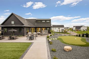 A building with a patio and a rock in the middle of a green area.