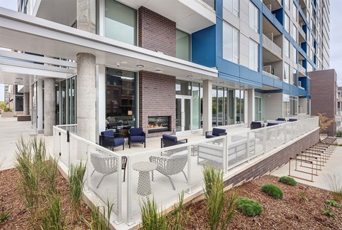 A modern building with a blue and white exterior and a white fence surrounding a patio area.