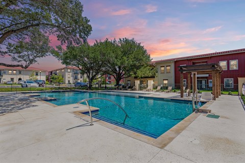 Affordable Apartments Near River Walk In N Park San Antonio, TX -The St. John - A Large Community Swimming Pool At Sunset With Arched Water Fountains And A Dark Wood Pergola.