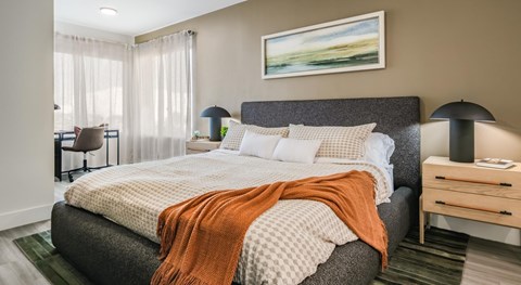 A bedroom with a large bed and a painting on the wall.