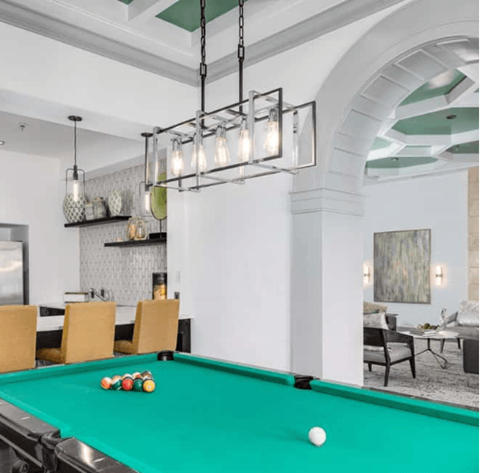 Billiard room with a green pool table, racked balls, and modern lighting fixtures.