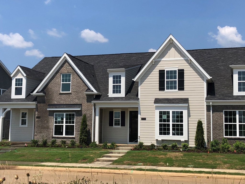 a home with white siding and brown brick and a black roof