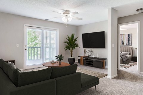 A living room with a green couch and a flat screen TV mounted on the wall.