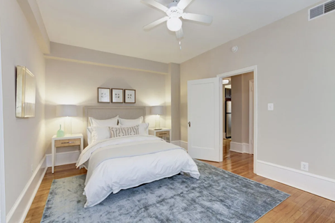 A bedroom with a large bed and a ceiling fan.