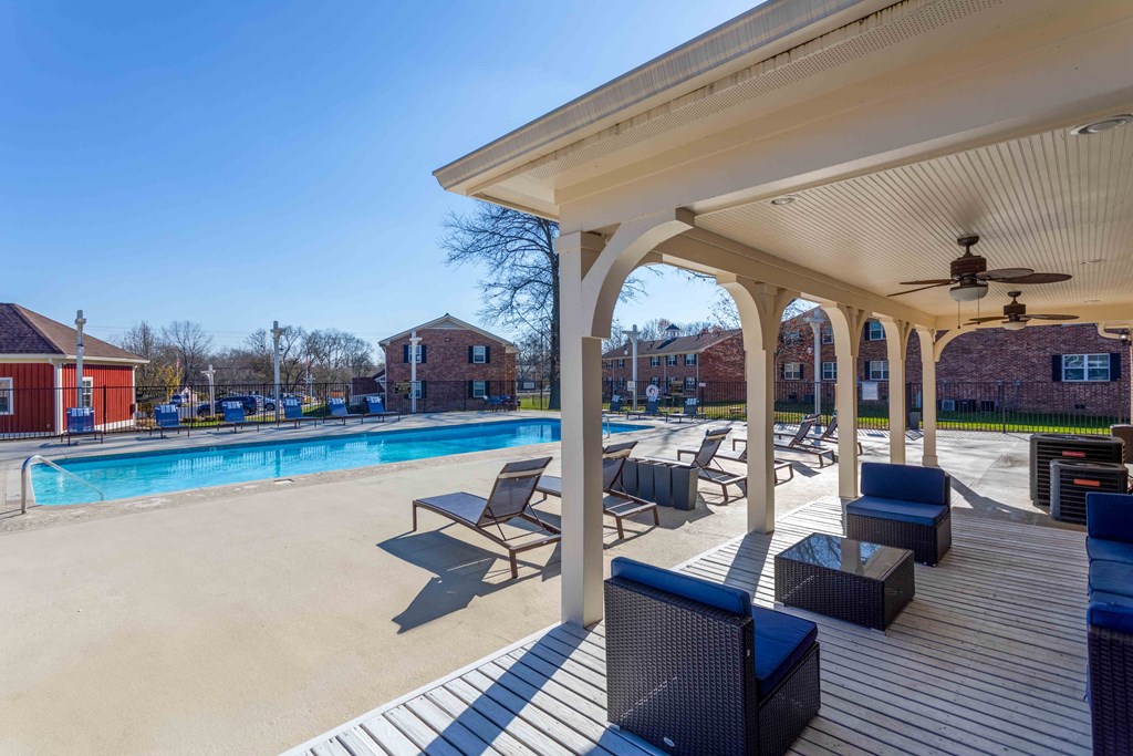 Apartment complex pool area with lounge chairs and covered patio.