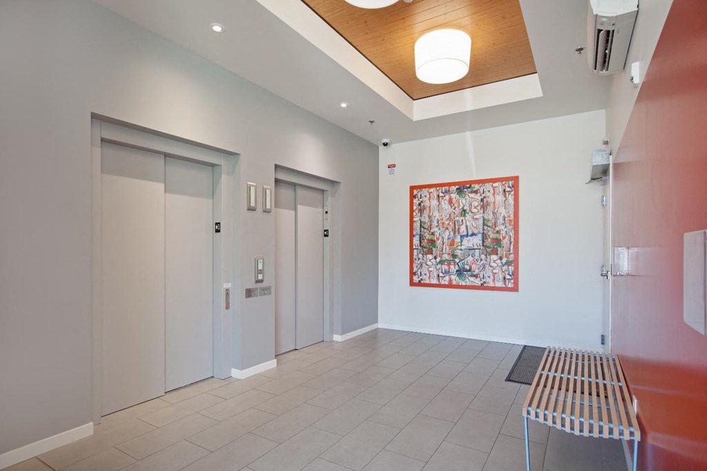 a room with two doors and a bench with a painting on the wall