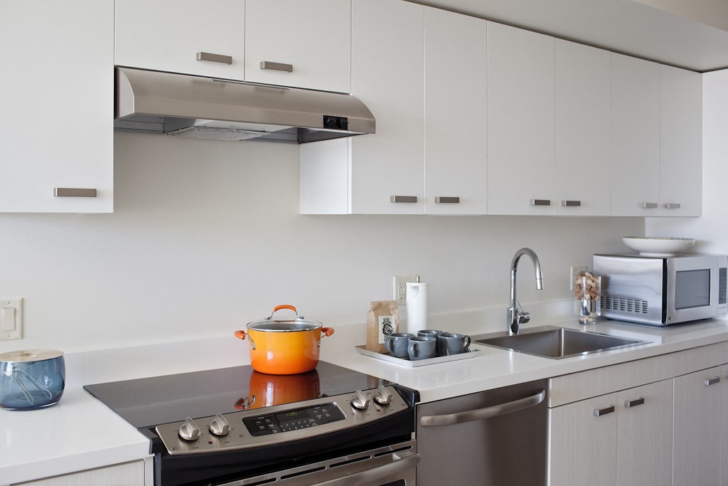 Apartments for Rent in Beaverton, OR - Westline - Well Lit Kitchen with White Cabinetry, White Countertops, Stainless Steel Appliances, and Silver Accents