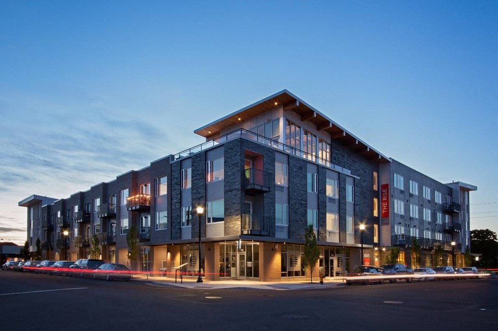 Apartments for Rent in Beaverton - Westline - Grey Brick Apartment Building with Large Windows, Parked Cars, Balconies, and Trees