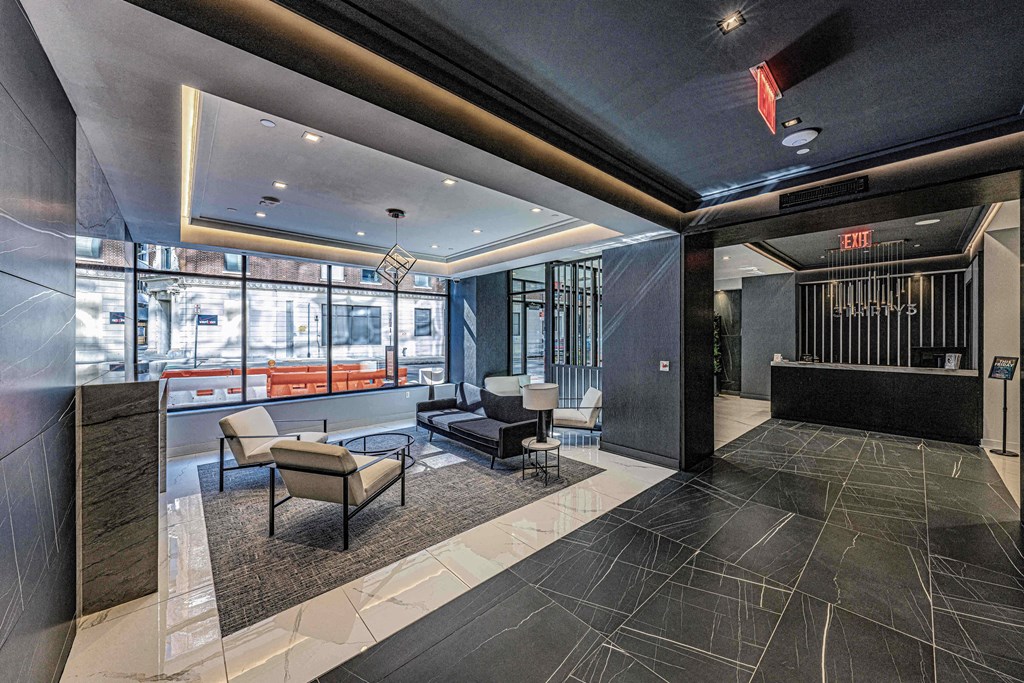 Lobby of 3thirty3 New Rochelle NY high-rise, with fireplace, marble floors, modern furniture, floor-to-ceiling windows with street view, and concierge desk.