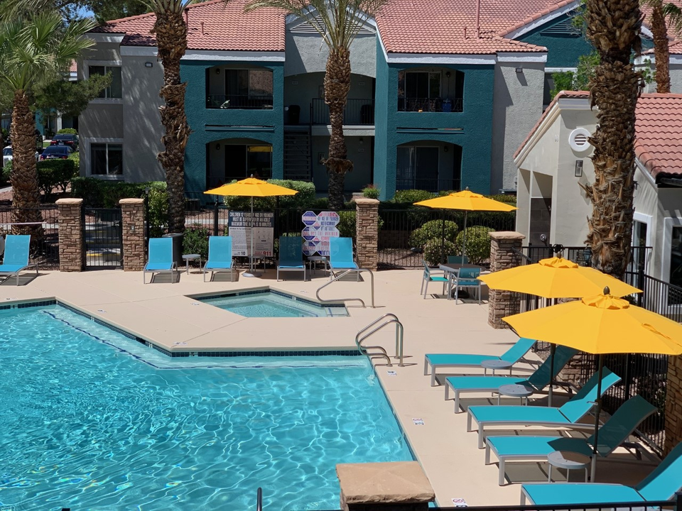 Apartments in Las Vegas, NV - Cimarron - Resort-Style Pool with a Spa, Lounge Chairs, Umbrellas, and Palm Trees