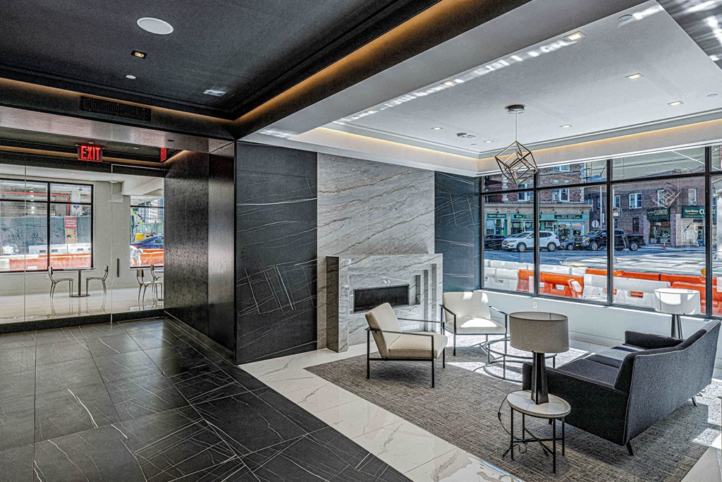 Lobby of 3thirty3 New Rochelle NY high-rise. Features fireplace, marble floors, modern seating, and floor-to-ceiling windows with street view.