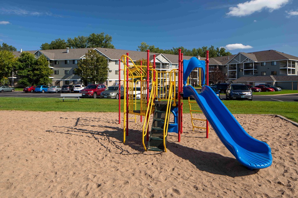A playground with a blue slide and yellow and red climbing structure.