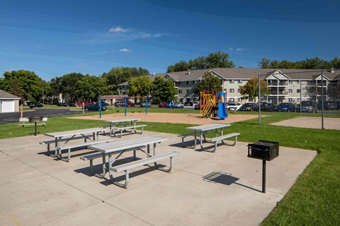 A playground with a slide and picnic tables.