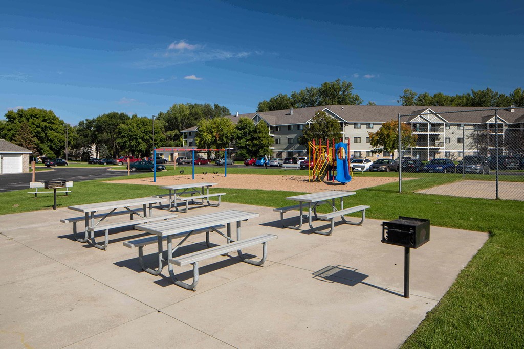 A playground with a slide and picnic tables.