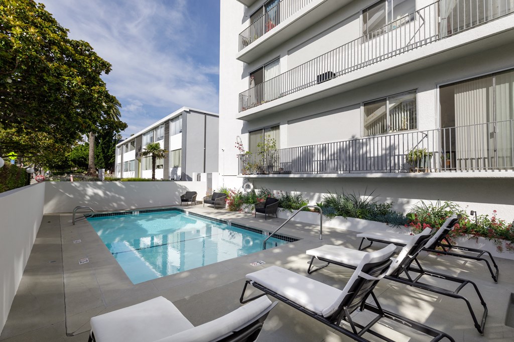Two BR Apartments in Santa Monica CA - San Vicente Tower - Sparkling Pool Surrounded by Lounge Seating and View of Apartment Building
