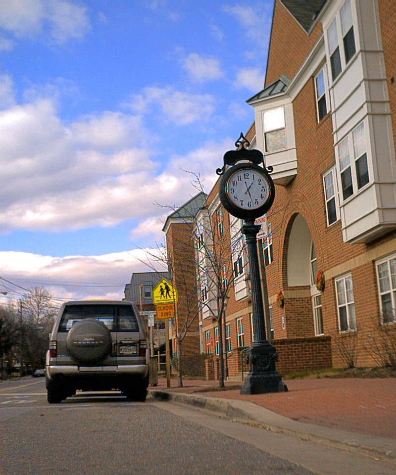 A street scene with a clock and a car.
