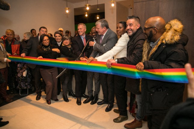 a group of people standing around a ribbon cutting