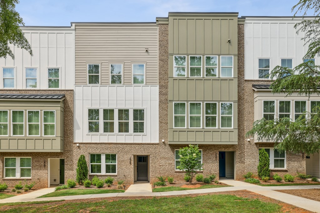 Outdoor scene featuring townhome buildings and lush greenery at Henley Avondale in Avondale Estates, GA, within a pet-friendly community.