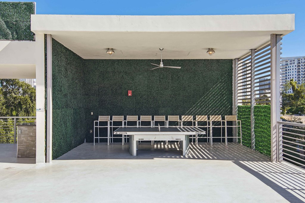 1- & 2-Bedroom Apartments for Rent in Miami, FL – Riverview One Apartments – A patio with a ping pong table and chairs under a white roof.