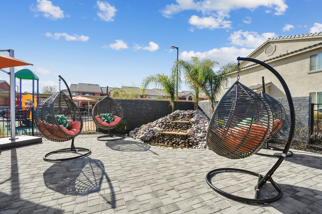 Four hanging chairs are placed on a patio.