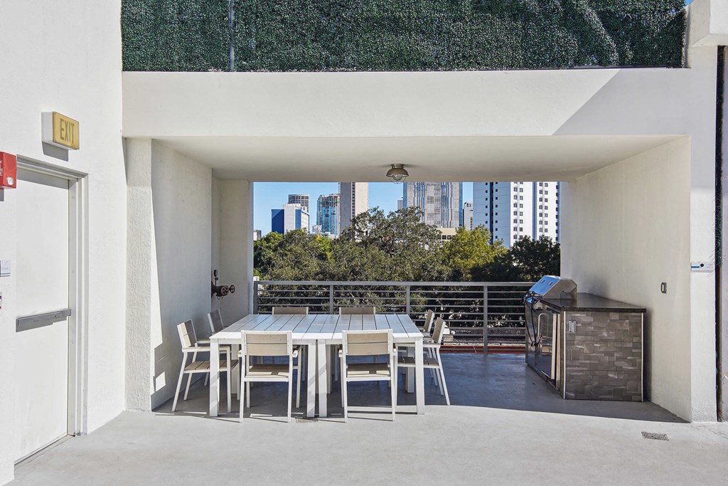 1- & 2-Bedroom Apartments for Rent in Miami, FL – Riverview One Apartments – A patio with a table and chairs overlooking a cityscape.