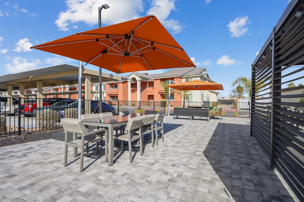 A patio with a table and chairs under an orange umbrella.