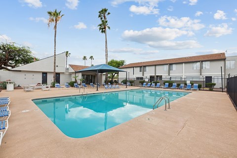 A large swimming pool with a blue cover and a building in the background.