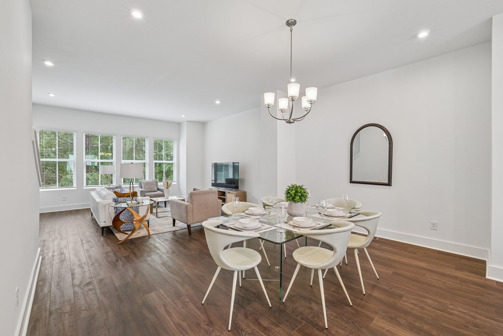 A dining room with a glass table and white chairs.