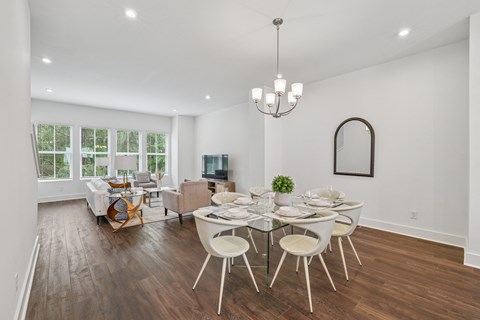 A dining room with a glass table and white chairs.