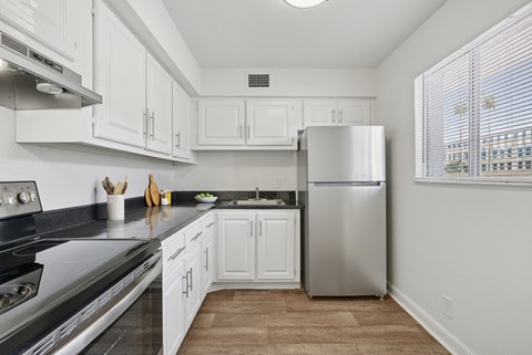 A kitchen with white cabinets and a stainless steel refrigerator.