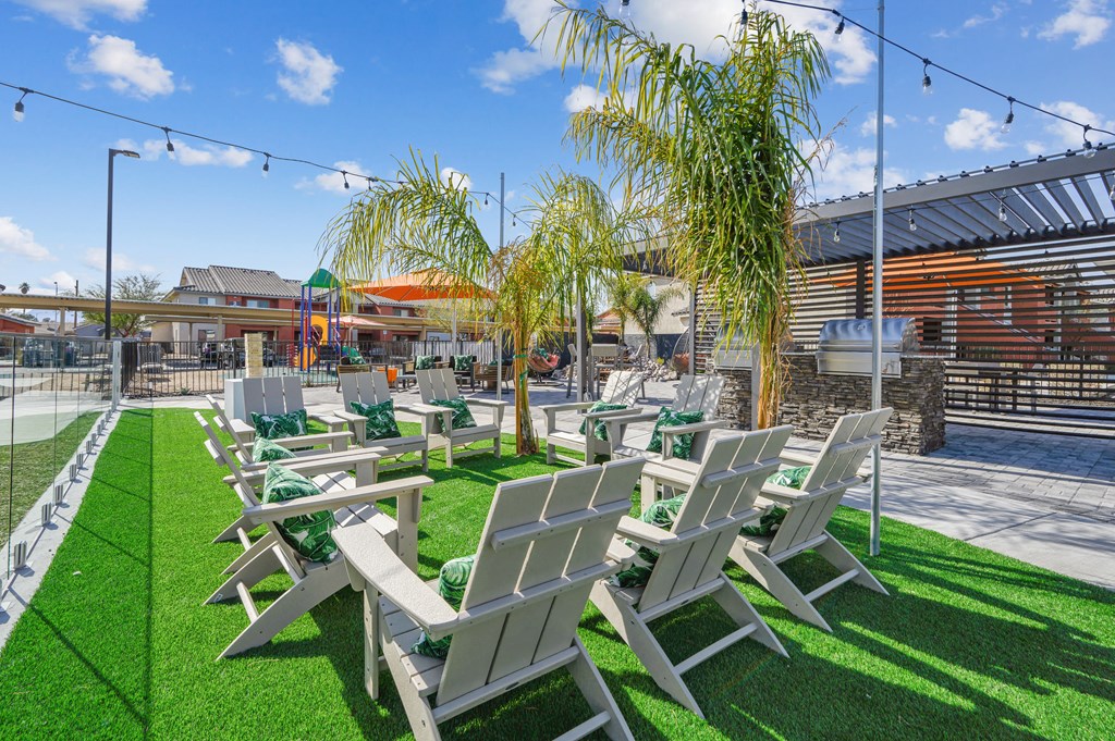 A row of white chairs are lined up on a green lawn.