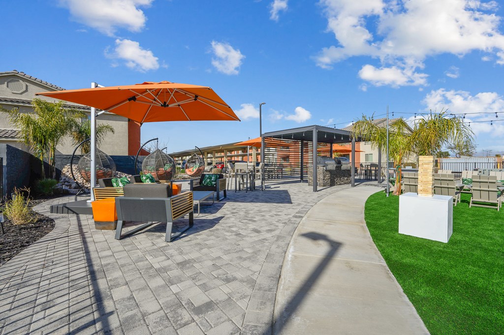 A sunny day at a park with a bench and a shade umbrella.