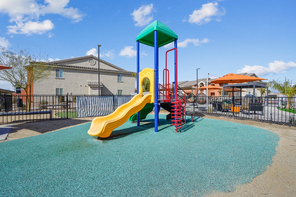 A playground with a yellow slide and a blue and green top.