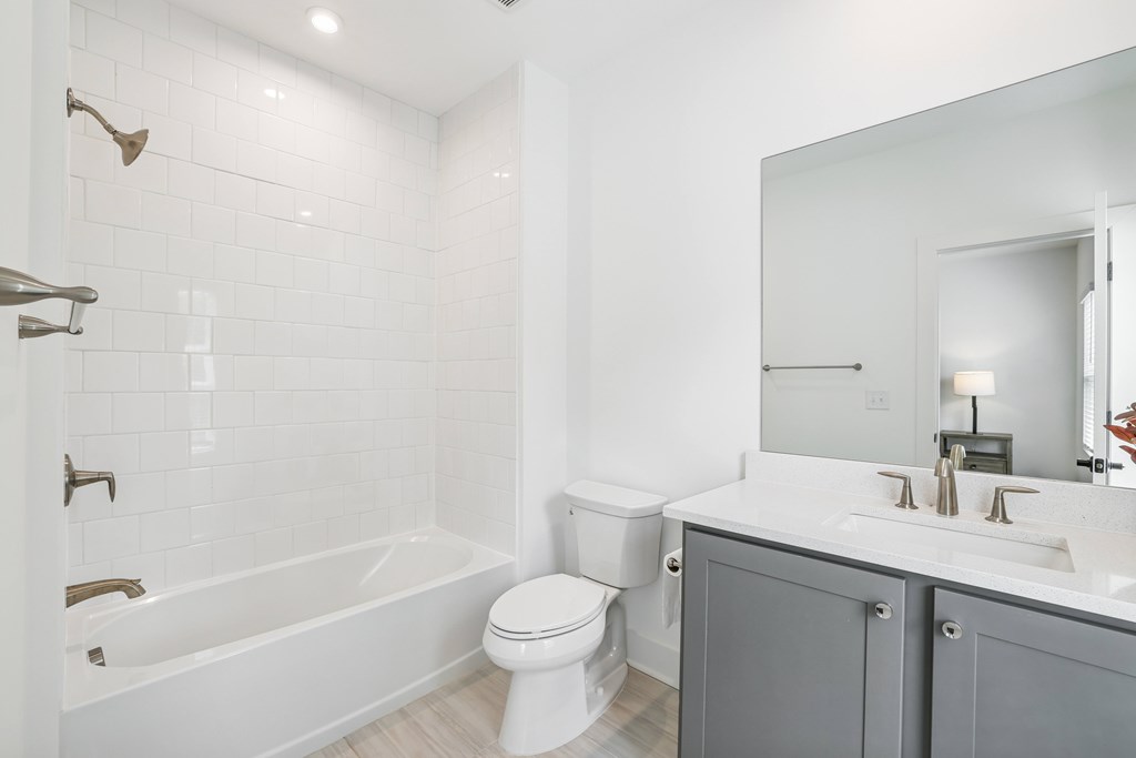 Bathroom with tub, shower, sink, and large mirror at Henley Avondale in Avondale Estates, GA, in a pet-friendly community.